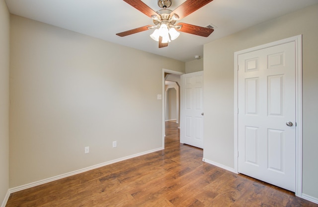 unfurnished bedroom with ceiling fan and dark wood-type flooring