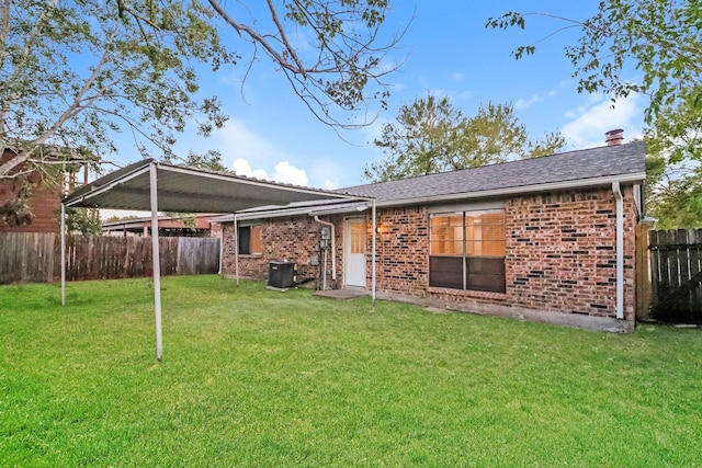 back of house with central air condition unit and a yard