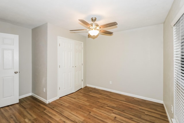 unfurnished bedroom featuring ceiling fan, a closet, and dark wood-type flooring