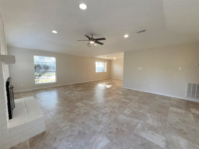 spare room with ceiling fan, plenty of natural light, and a brick fireplace