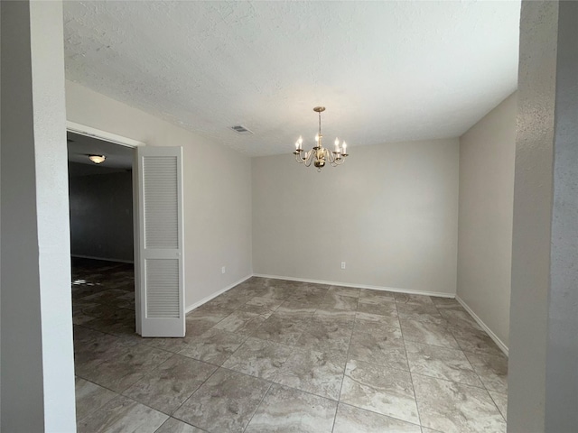 empty room with a chandelier and a textured ceiling