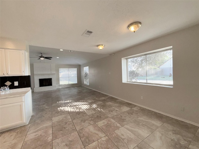 unfurnished living room featuring a brick fireplace and ceiling fan