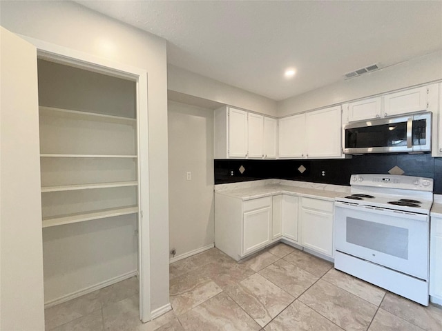 kitchen featuring white electric range oven, light tile patterned floors, and white cabinetry