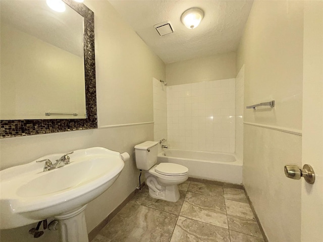 full bathroom featuring a textured ceiling, toilet,  shower combination, and sink