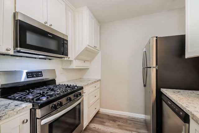 kitchen with white cabinets, stainless steel appliances, and tasteful backsplash