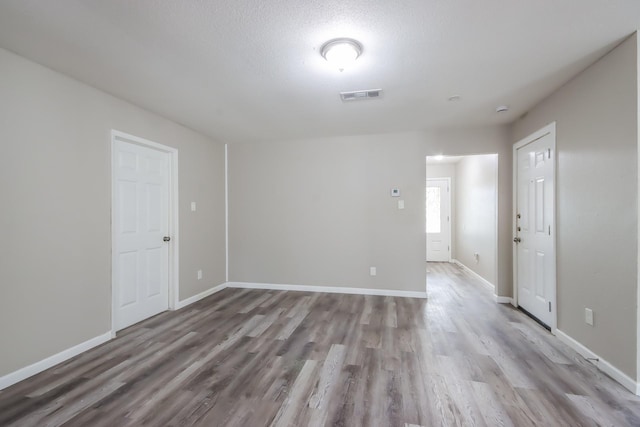 spare room featuring light hardwood / wood-style floors and a textured ceiling