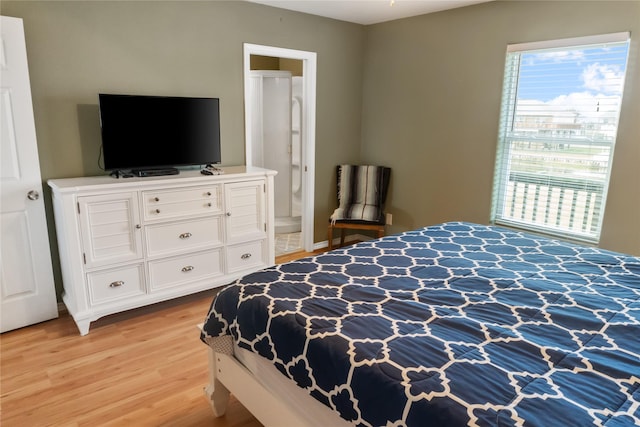 bedroom with ensuite bathroom and light hardwood / wood-style flooring