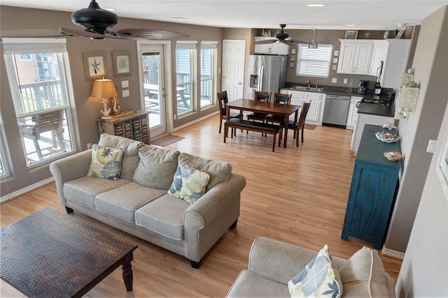 living room featuring ceiling fan, light wood-type flooring, and sink