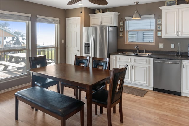 kitchen with sink, pendant lighting, light hardwood / wood-style floors, white cabinets, and appliances with stainless steel finishes