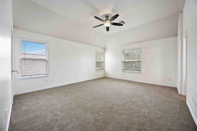 empty room with a healthy amount of sunlight, dark carpet, and vaulted ceiling