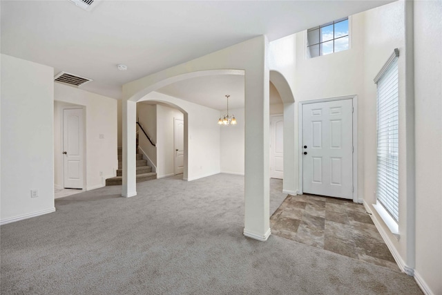 entryway featuring light colored carpet and an inviting chandelier