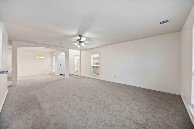 carpeted empty room with ceiling fan with notable chandelier