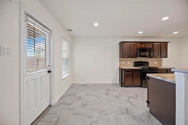 kitchen featuring light stone countertops, dark brown cabinetry, decorative backsplash, and black appliances