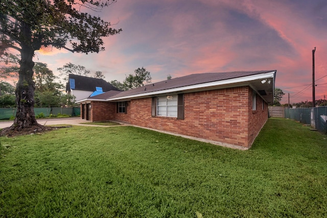 back house at dusk with a lawn