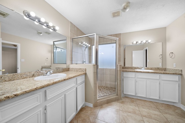 bathroom featuring tile patterned flooring, vanity, a textured ceiling, and walk in shower