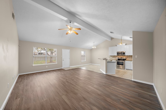 unfurnished living room with a textured ceiling, lofted ceiling with beams, light hardwood / wood-style floors, and ceiling fan with notable chandelier