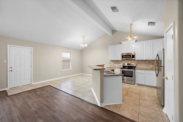 kitchen featuring appliances with stainless steel finishes, pendant lighting, lofted ceiling with beams, light hardwood / wood-style floors, and white cabinetry