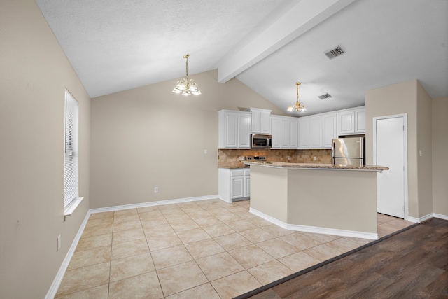 kitchen featuring lofted ceiling with beams, appliances with stainless steel finishes, decorative light fixtures, light hardwood / wood-style floors, and white cabinetry