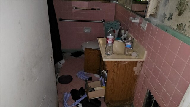 bathroom with toilet and tile walls