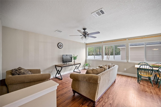 living room featuring a textured ceiling, hardwood / wood-style flooring, and ceiling fan