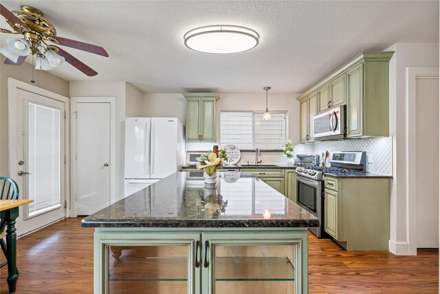 kitchen with a center island, sink, hanging light fixtures, stainless steel appliances, and green cabinets