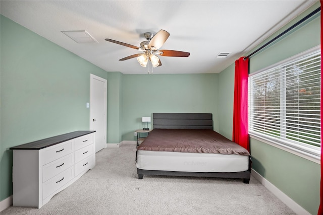 bedroom featuring multiple windows, light carpet, and ceiling fan