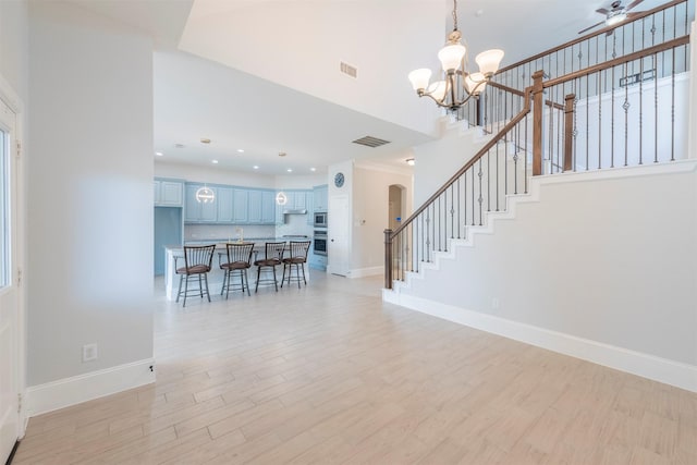 interior space featuring ceiling fan with notable chandelier and light wood-type flooring