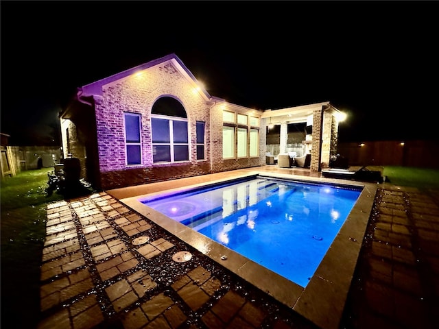 pool at twilight with an in ground hot tub and a patio