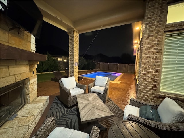 patio at twilight with an outdoor stone fireplace and a fenced in pool