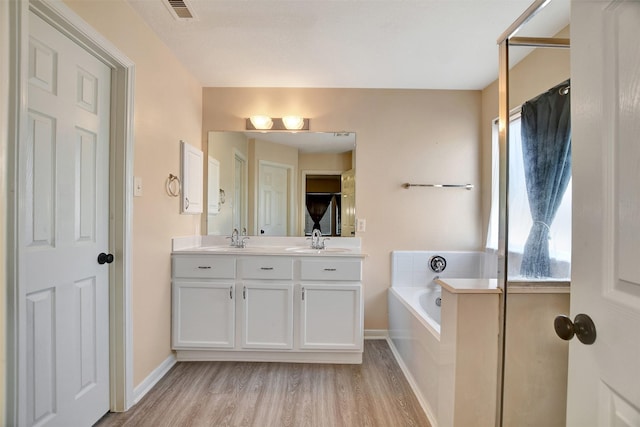 bathroom with vanity, a relaxing tiled tub, and hardwood / wood-style flooring