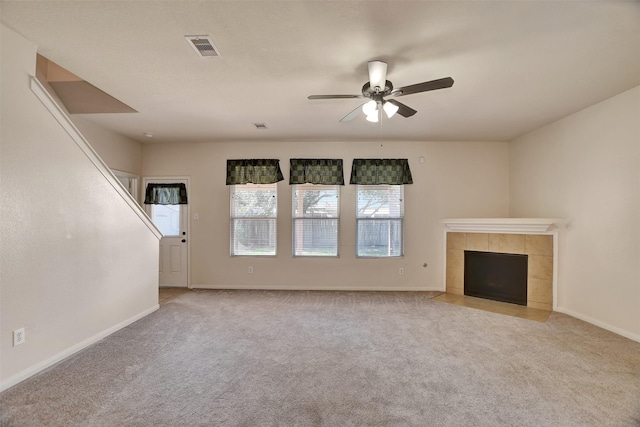 unfurnished living room featuring a tile fireplace, light carpet, and ceiling fan