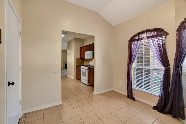 kitchen with vaulted ceiling, tasteful backsplash, light tile patterned floors, and white appliances