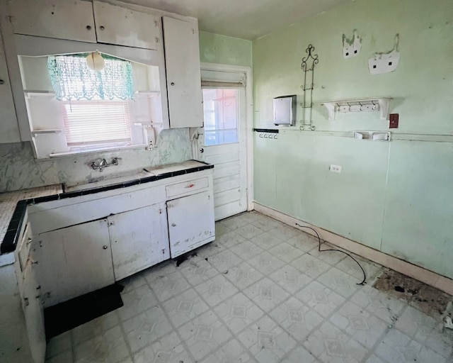 kitchen featuring backsplash, white cabinetry, a healthy amount of sunlight, and sink