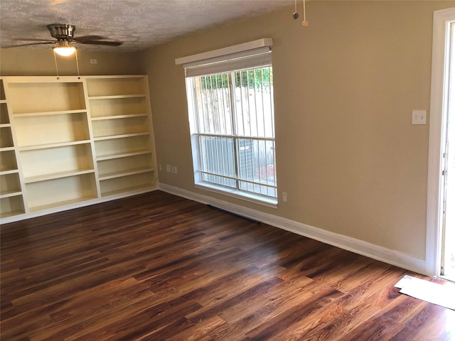 empty room featuring a textured ceiling, ceiling fan, and dark wood-type flooring