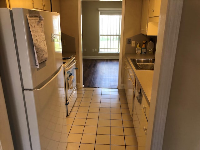 kitchen featuring white range with electric stovetop, light tile patterned flooring, sink, and fridge