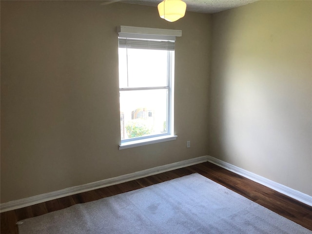 empty room featuring a textured ceiling and dark hardwood / wood-style floors