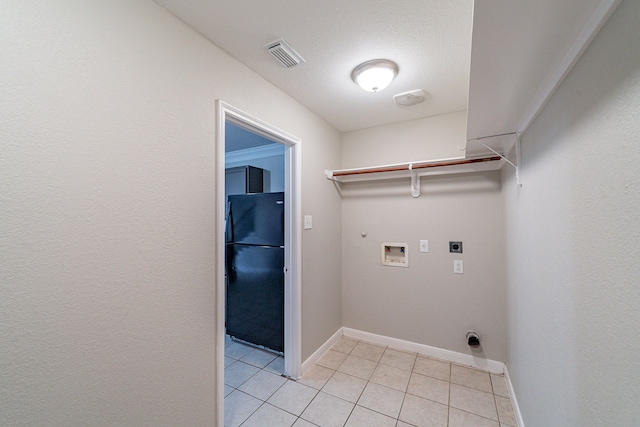 laundry room with hookup for an electric dryer, washer hookup, a textured ceiling, hookup for a gas dryer, and light tile patterned flooring