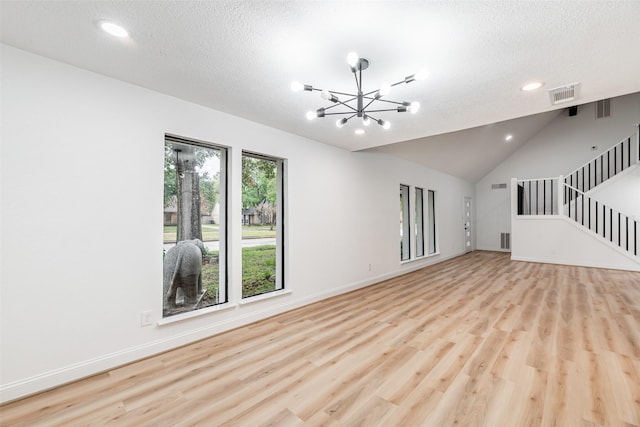 unfurnished living room featuring a textured ceiling, high vaulted ceiling, light hardwood / wood-style flooring, and a notable chandelier