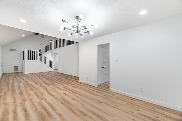 unfurnished living room with a chandelier, a textured ceiling, light wood-type flooring, and vaulted ceiling