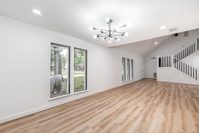 unfurnished living room featuring a notable chandelier, a textured ceiling, high vaulted ceiling, and light hardwood / wood-style flooring