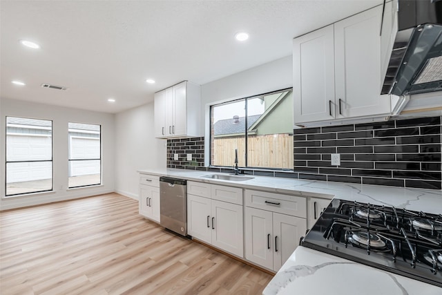 kitchen featuring backsplash, white cabinets, sink, light hardwood / wood-style flooring, and dishwasher