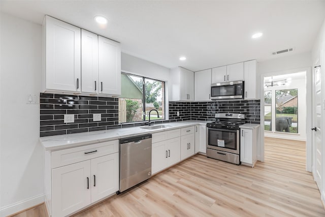 kitchen with white cabinetry, sink, stainless steel appliances, and light hardwood / wood-style flooring