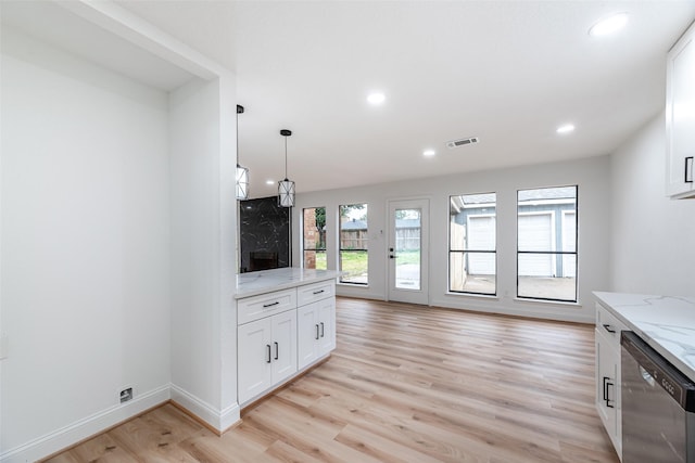 kitchen featuring a healthy amount of sunlight, light hardwood / wood-style flooring, stainless steel dishwasher, and light stone counters