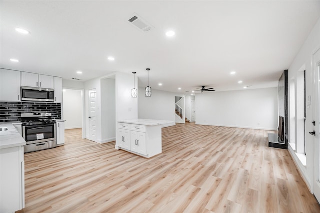 kitchen featuring white cabinets, stainless steel appliances, ceiling fan, and light hardwood / wood-style floors