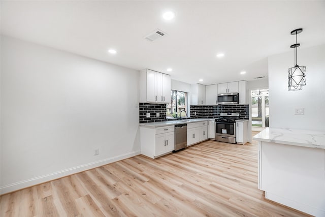 kitchen with light stone countertops, stainless steel appliances, light hardwood / wood-style flooring, pendant lighting, and white cabinets