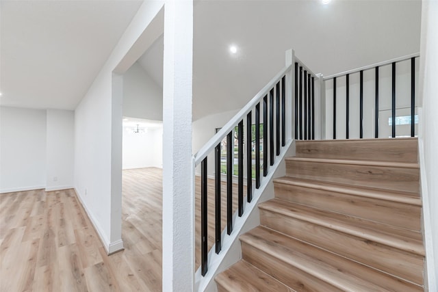 staircase featuring hardwood / wood-style floors and lofted ceiling