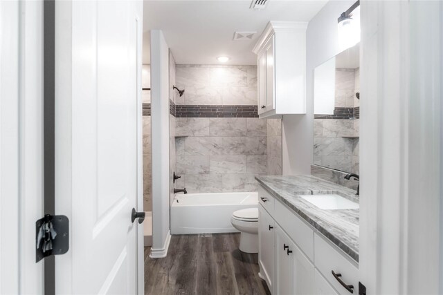 full bathroom with hardwood / wood-style floors, vanity, toilet, and tiled shower / bath