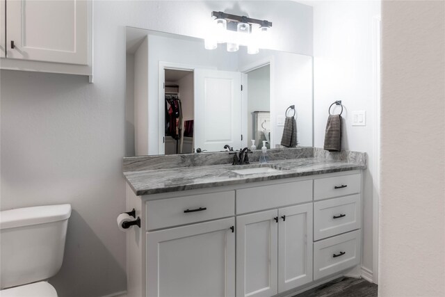 bathroom with hardwood / wood-style floors, vanity, and toilet