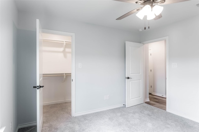 unfurnished bedroom with ceiling fan, a spacious closet, light carpet, and a closet