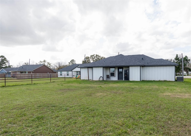 rear view of property featuring a lawn and central AC